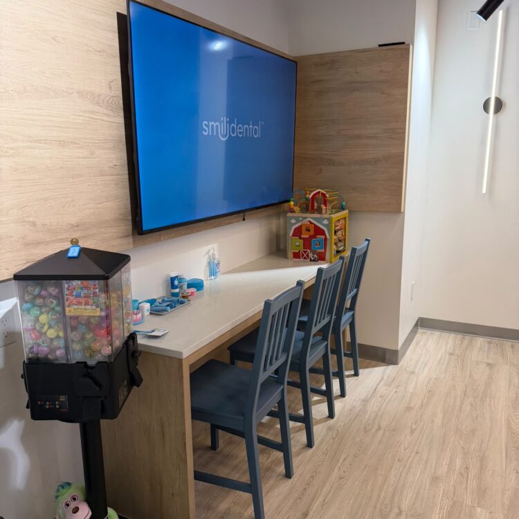 Kids play area with toys, a treasure tower prize machine and TV at Smili Dental in North Vancouver